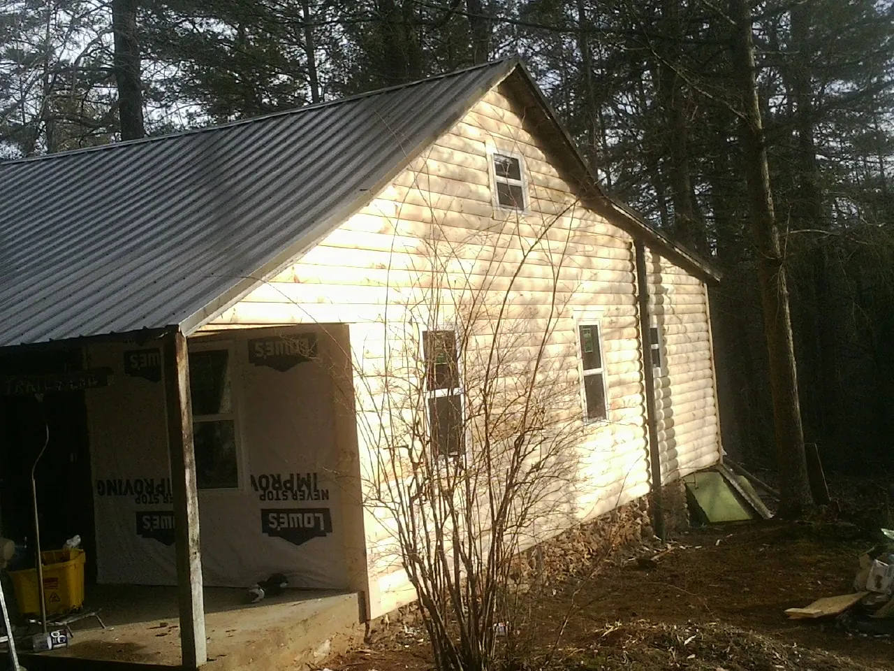 Log siding gable end under a dark metal roof edge in Osceola