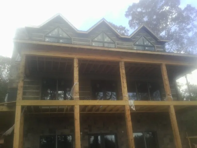 Dormers and porch framing on a large log home under construction — Roof Coating work by our crew in Osceola